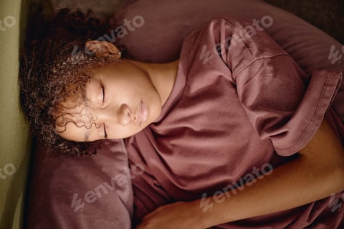 Preview: Teenage Girl Resting Indoors with Eyes Closed on Soft Cushion