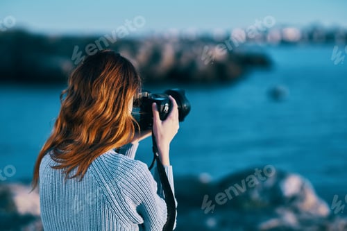Preview: woman taking pictures on camera sea in mountains back view