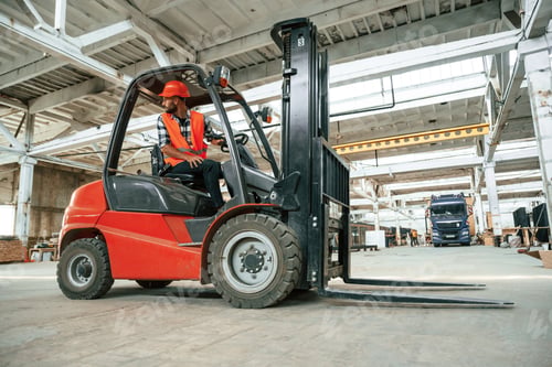 Preview: Driving the forklift. Industrial worker in wooden warehouse