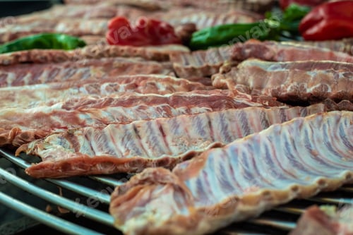 Preview: Raw pork ribs on a grill on a barbecue.