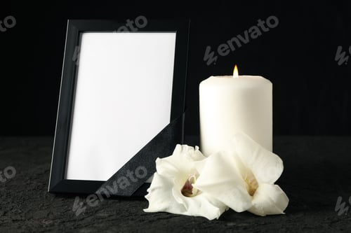 Preview: Photo frame with black ribbon, candle and flowers on black background