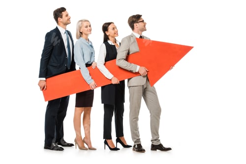 Preview: young smiling businesspeople holding big red arrow together isolated on white