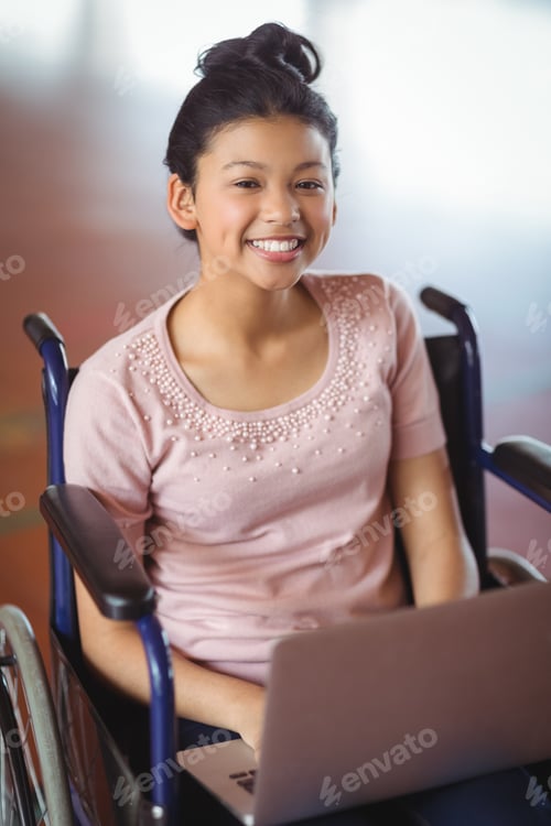 Preview: Portrait of disabled schoolgirl using laptop in campus