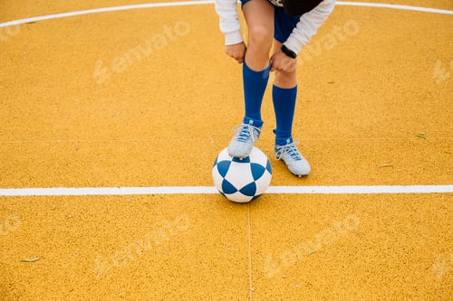 Preview: Little unrecognizable boy playing soccer of yellow background