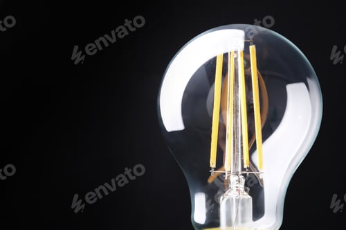 Preview: New modern lamp bulb on black background, closeup. Space for text