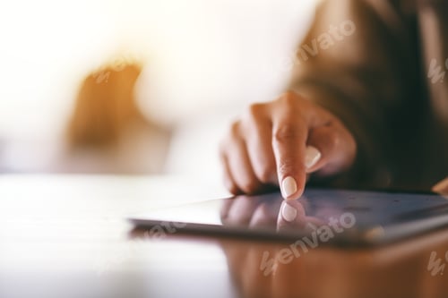 Preview: Closeup image of a woman pointing finger at tablet pc on wooden table