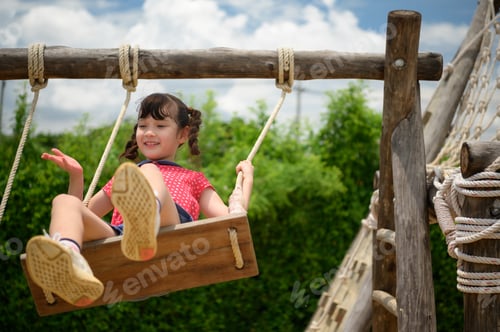 Preview: A little girl having fun swinging on a swing on a clear day