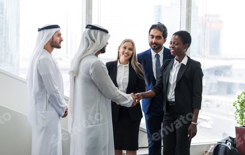 Preview: Mixed business team in Dubai. Business meeting with men wearing kandura and western people in the