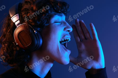 Preview: Male singer wearing headphones listening to music and singing with his mouth open, sound recording