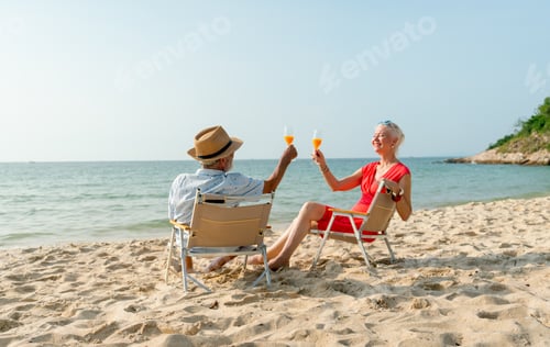 Vista previa: Back of senior man hold glass of orange juice and cheers to his wife during sit on beach chair