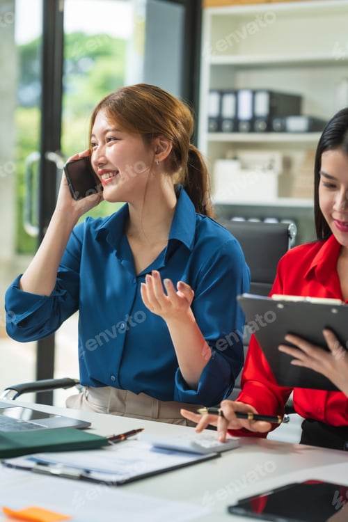 Preview: Two Asian business woman work at a desk, discussing business strategies, marketing, plans analyze