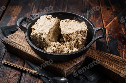 Preview: Halva with sunflower seeds and honey in pan. Wooden background. Top view