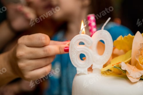 Preview: Closeup shot of a female lighting candles for the 60th birthday