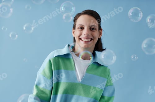 Preview: Smiling teenage girl with disability with bubbles on blue