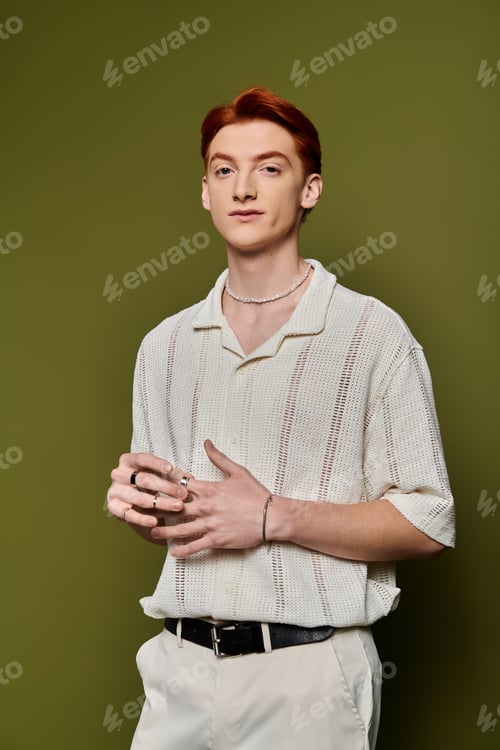 Preview: Confident young man in stylish outfit stands against a green backdrop, exuding charm