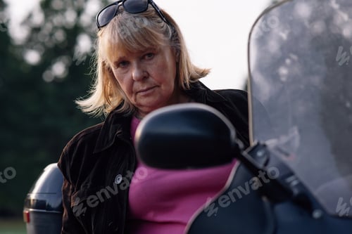 Preview: Hobby Motorcycle tourism. Looking at camera adult blonde motorcycle tourist, sitting on her bike.