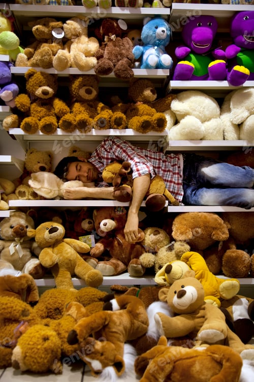 Preview: Man sleeping on a shelf between soft toys in a supermarket