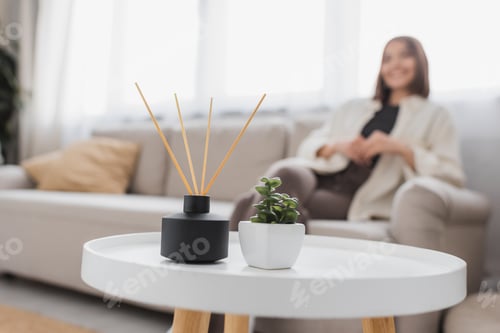Preview: Bamboo aroma sticks and plant on coffee table near blurred woman at home