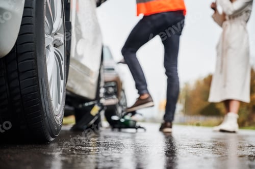 Preview: Emergency auto mechanic repairing woman vehicle on the street.