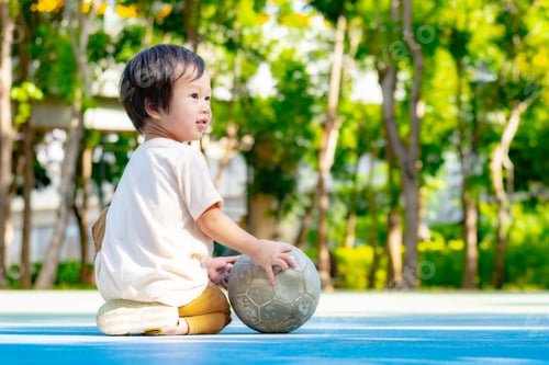 Preview: A peaceful Asian toddler boy 2-3 years, kneels on a bright blue playground floor.
