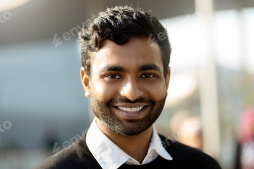 Preview: Smiling confident Indian student looking at camera standing in university campus. Education