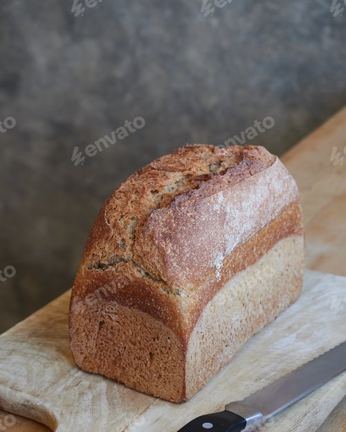 Preview: homemade whole wheat bread, tin loaf, on a wooden board on the kitchen table