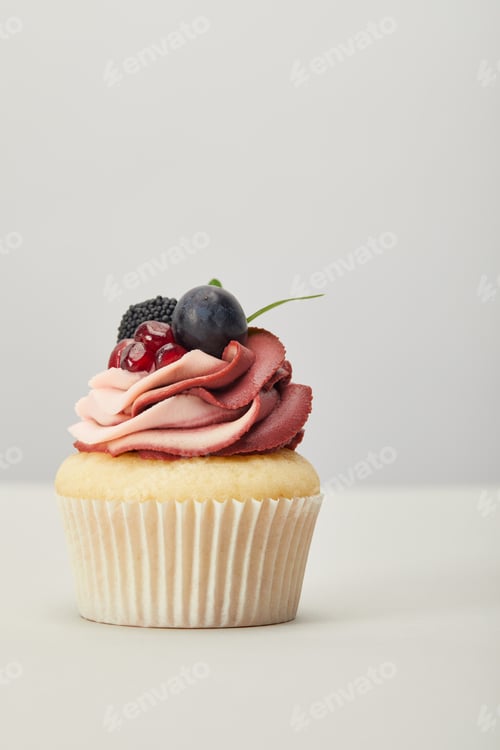 Preview: cupcake with cream, garnet, grape and blackberry isolated on grey