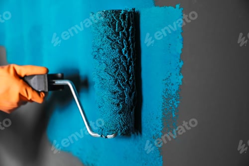 Preview: Woman painting grey wall with blue dye, closeup
