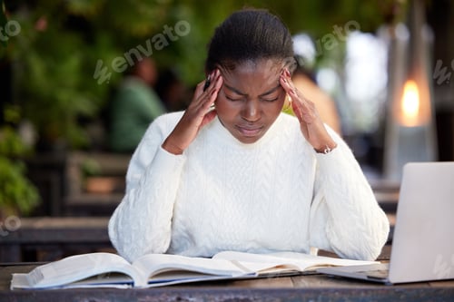 Preview: Shot of a young woman looking stressed while studying in a cafe