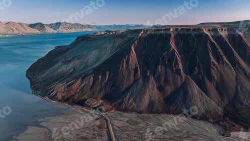 Preview: Majestic volcanic landscape of Svalbard showcasing dramatic cliffs and serene waters at dusk