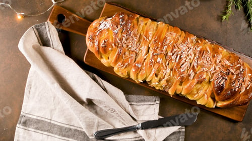 Preview: Braided holiday sweet bread with almond glaze and slivers, served on a dark wood cutting board