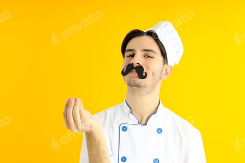 Preview: Concept of cooking, young man chef on yellow background