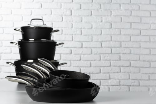 Preview: Set of cookware on table against white brick wall
