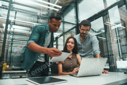 Preview: Searching for solutions. Group of three young and positive employees using modern technologies and