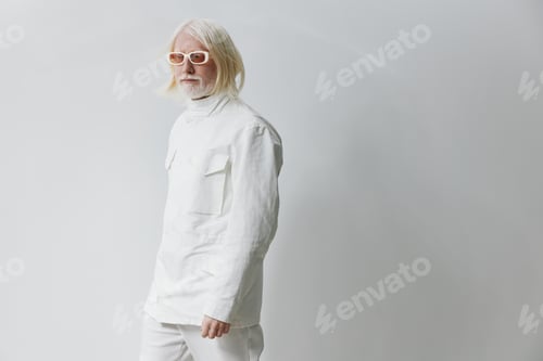 Preview: Fashionable elderly man wearing white outfit and sunglasses on a light grey background, embodying a