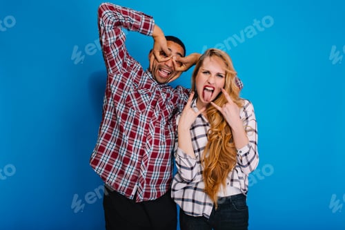 Preview: Portrait funny moments of excitedcouple fooling around to camera on blue background. Having fun, wee