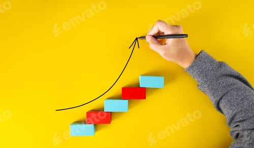 Preview: Male hand drawing an upward pointing arrow on top of growing graph made of wooden blocks