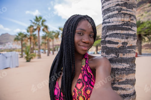 Preview: A beautiful african girl on vacation takes a selfie at a tropical beach.