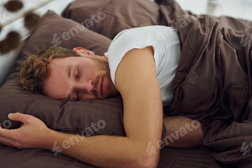 Preview: Man sleeps on the bed. Interior and design of beautiful modern bedroom at daytime