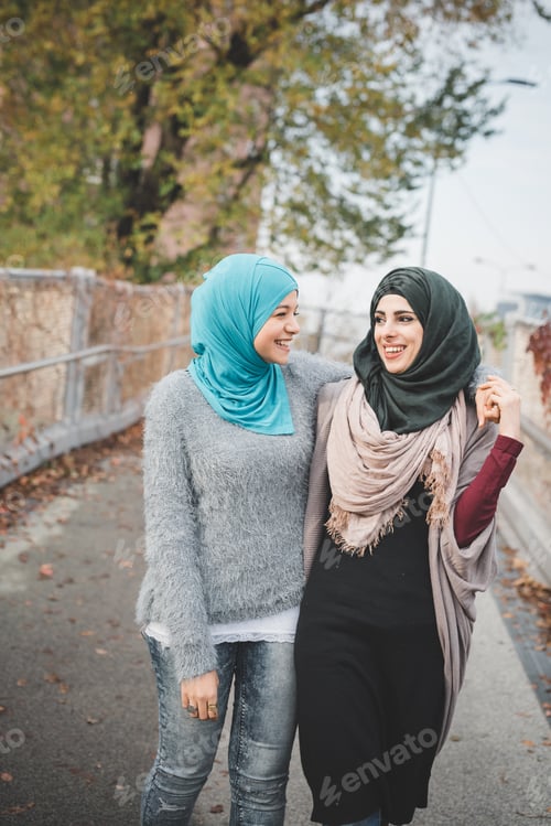 Preview: Two young female friends walking and chatting on park path