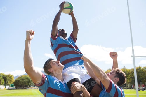 Preview: Happy rugby team enjoying victory while standing at field