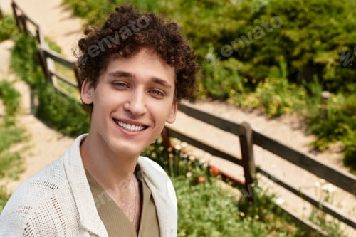 Preview: Stylish young man enjoying a sunny day in a vibrant green park
