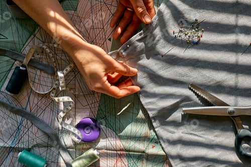 Preview: Woman sketching pattern on a linen fabric. Seamstress basting and sewing in a small studio
