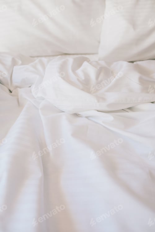 Preview: Bed and white linens in a hotel room.