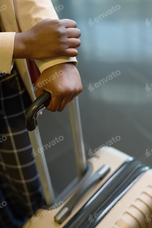 Preview: Hands of young elegant black woman holding by handle of suitcase with luggage