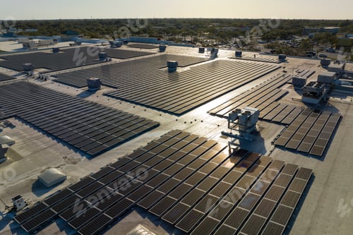 Preview: Aerial view of blue photovoltaic solar panels mounted on industrial building roof