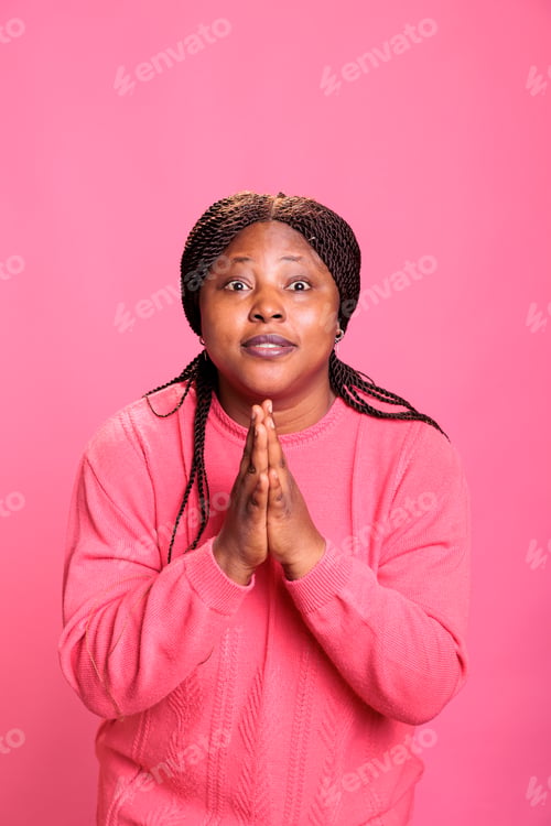Preview: African american woman doing prayer hands symbol in studio