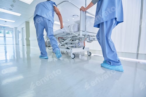 Preview: Two medics urgently pushing hospital bed in corridor