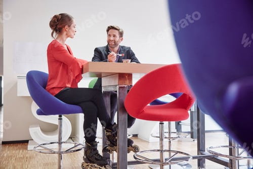 Preview: Man and woman with inline skates having lunch break in office