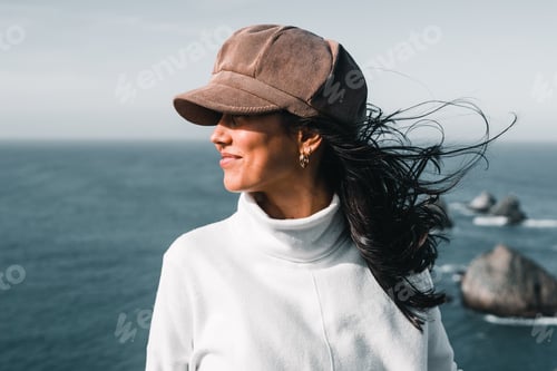 Preview: brunette caucasian girl in profile with nice white sweater hat black hair moved by the force of the